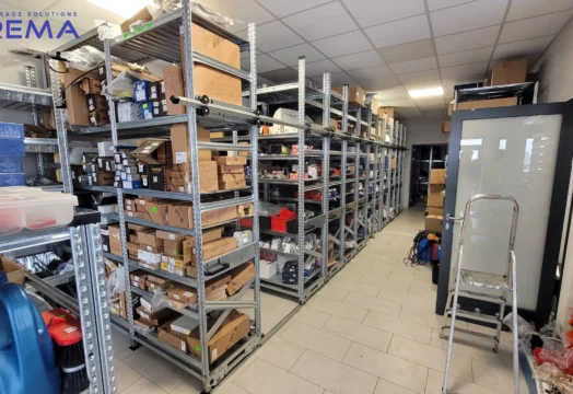 regały przesuwne w magazynie, mobilne magazynowe z towarem na półkach