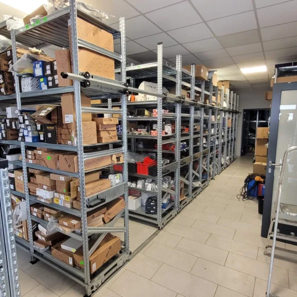 regały przesuwne w magazynie, mobilne magazynowe z towarem na półkach